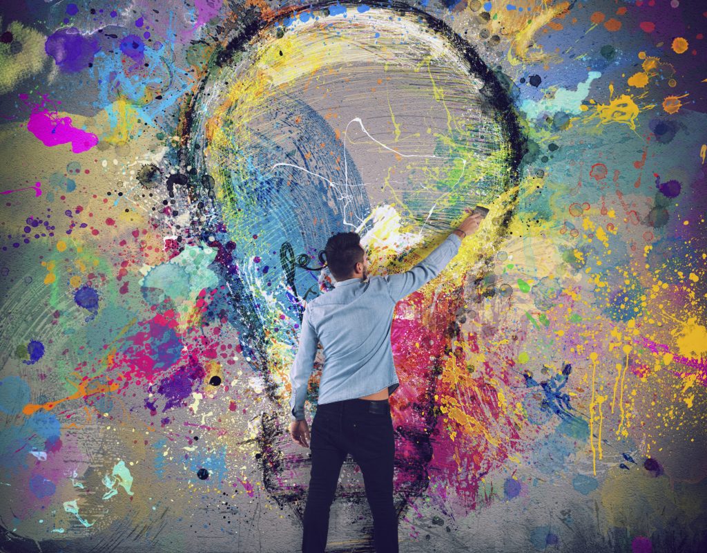 Boy draws with a brush an abstract big light bulb. Concept of innovation and creativity